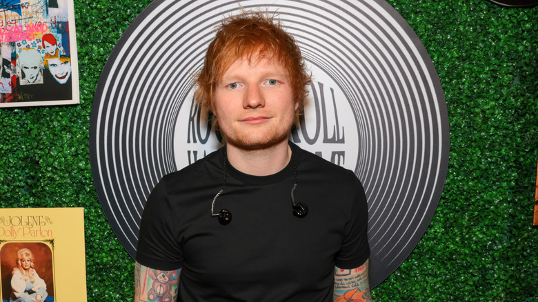 Ed Sheeran posing in front of a leafy background