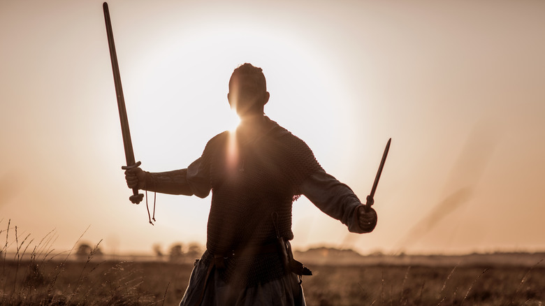 viking holding up swords on moors