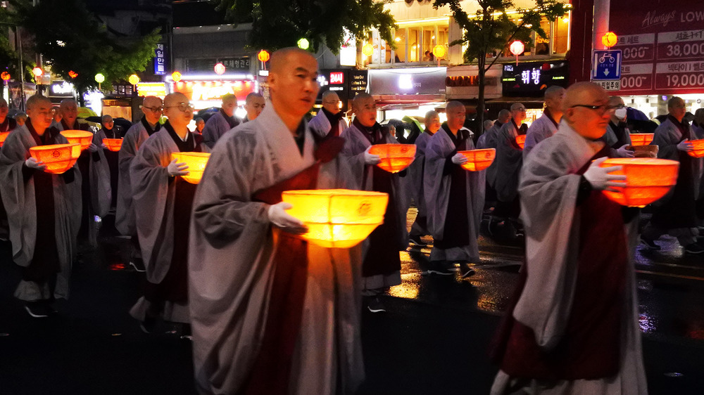 buddhist monks walking with lit lanterns