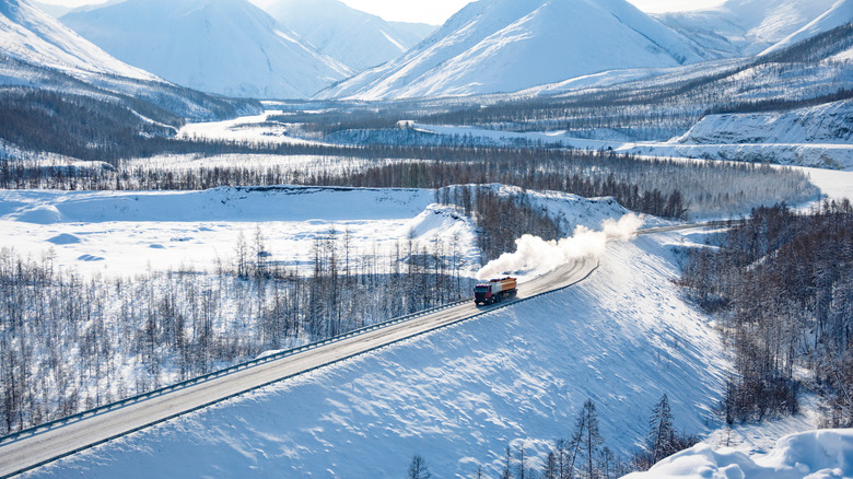 a lone truck traverses the Road of Bones amongst snowcapped mountains