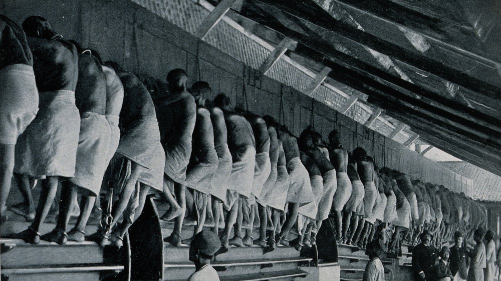 A long line of men are working a treadmill in Burma (modern-day Myanmar), 1890s