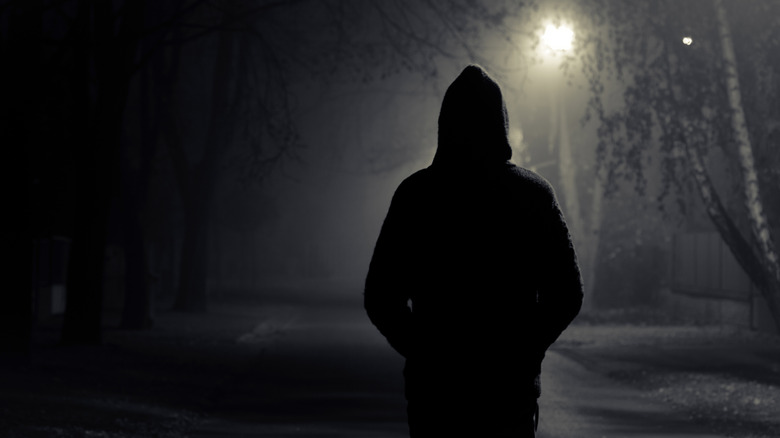 silhouette hooded figure walking at night