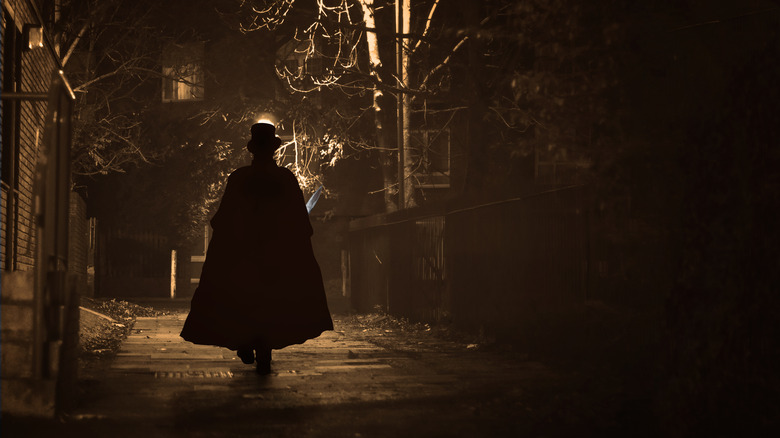 shadowy figure walking down street in cape