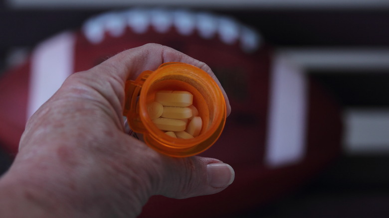 a football and a hand holding a bottle of pills