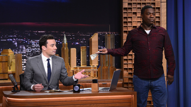 Tracy Morgan handing Jimmy Fallon some money on the set of The Tonight Show