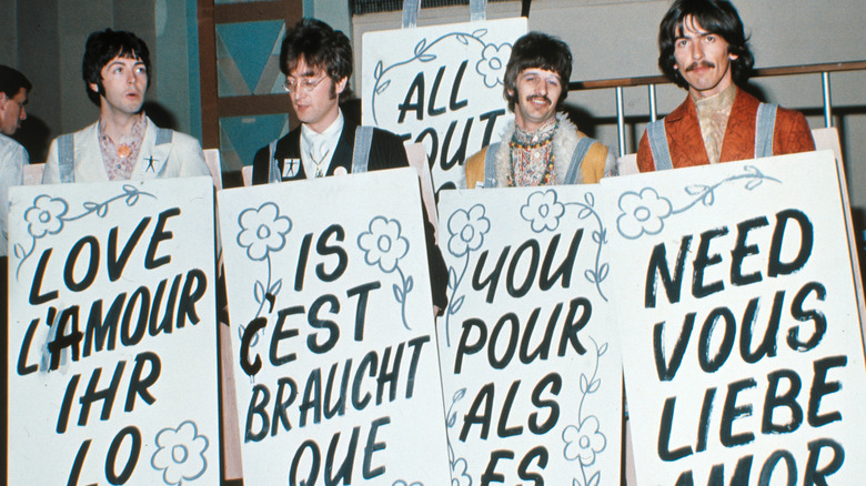 The Beatles holding up signs at a press event