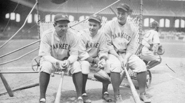 Baseball players Babe Ruth, Shawkey, and Lou Gehrig sitting on a batting practice backstop on the field at Comiskey Park in 1930