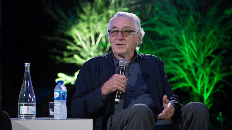 Robert De Niro sat talking into a microphone at a film festival