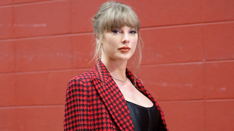 Taylor Swift in red by red brick wall