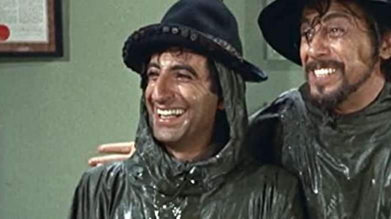 Jamie Farr smiling in wet poncho