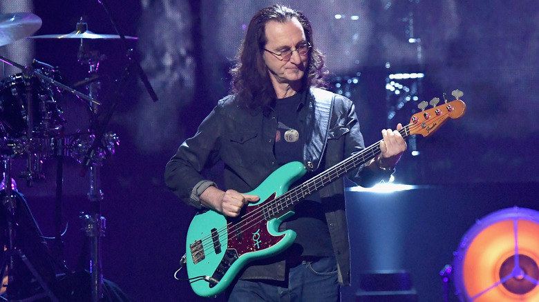 Rush's Geddy Lee playing a green bass guitar on stage