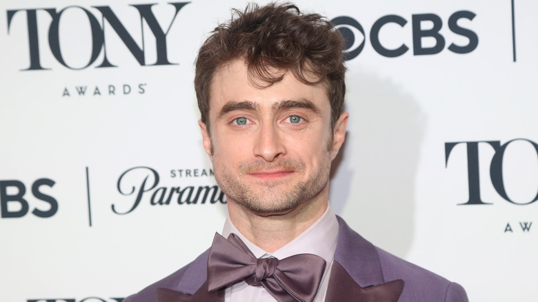 Daniel Radcliffe wearing a purple bowtie and posing for a photo