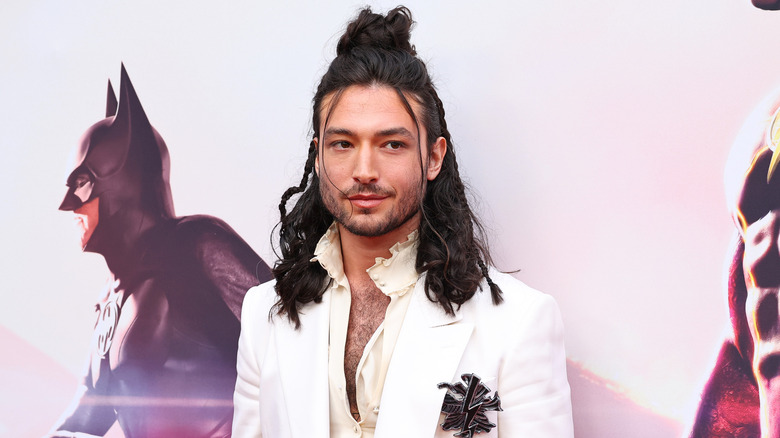 Long-haired Ezra Miller wearing white and posing on the red carpet