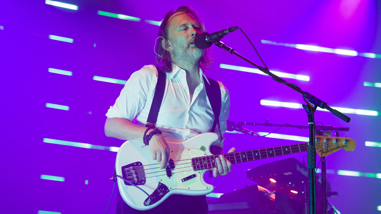 Thom Yorke singing on stage and playing bass guitar