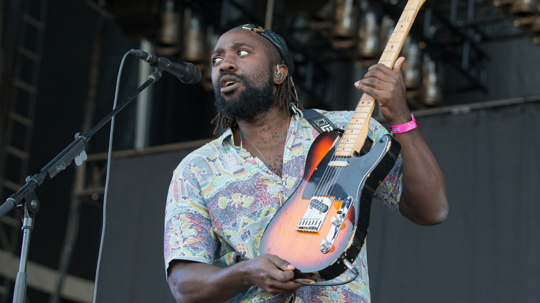 Kele Okereke of Bloc Party playing guitar onstage