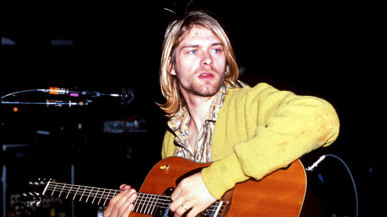 Kurt Cobain in yellow cardigan with acoustic guitar