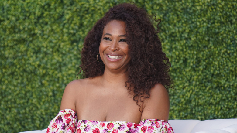 Tanika Ray smiling with greenery in the background