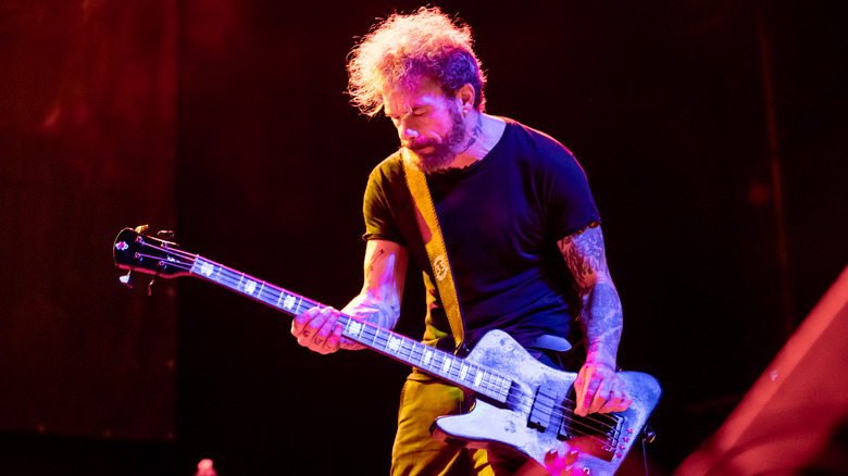 Jason Christopher playing bass on stage red-lit