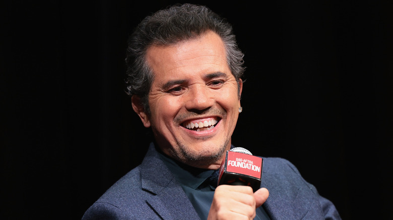 John Leguizamo smiling holding a microphone