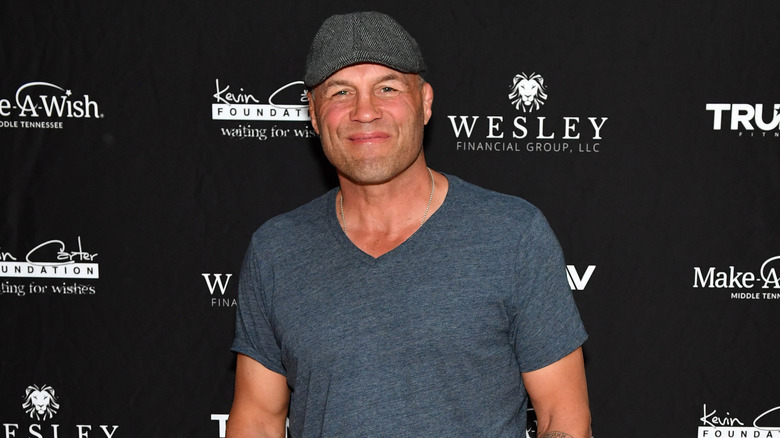 Randy Couture in a grey shirt and cap at an event