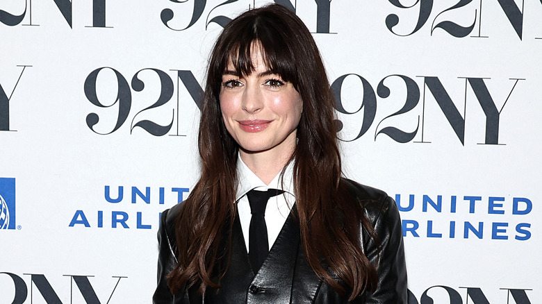 Smiling Anne Hathaway wearing a jacket and tie