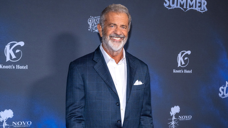 Smiling Mel Gibson wearing a white shirt and navy blazer