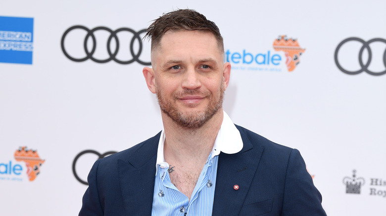 Smiling Tom Hardy wearing a blue shirt and a blazer