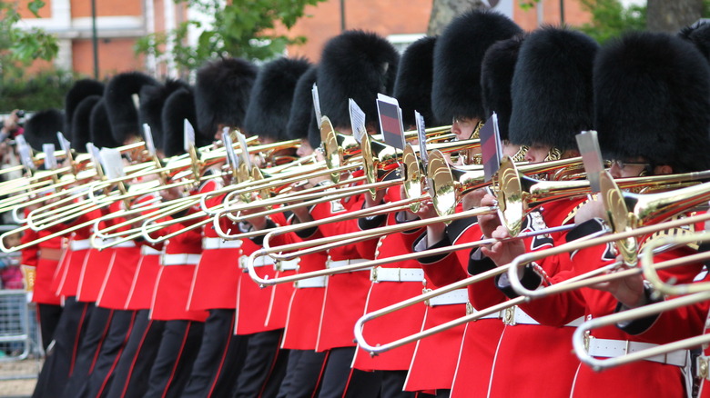 Soldiers red uniforms black wooly hats brass trumpets