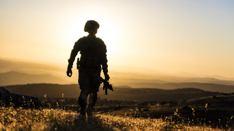 Uniformed soldier standing alone silhouette dusk