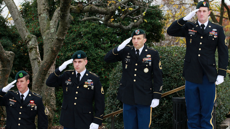 Four Green Berets saluting on steps