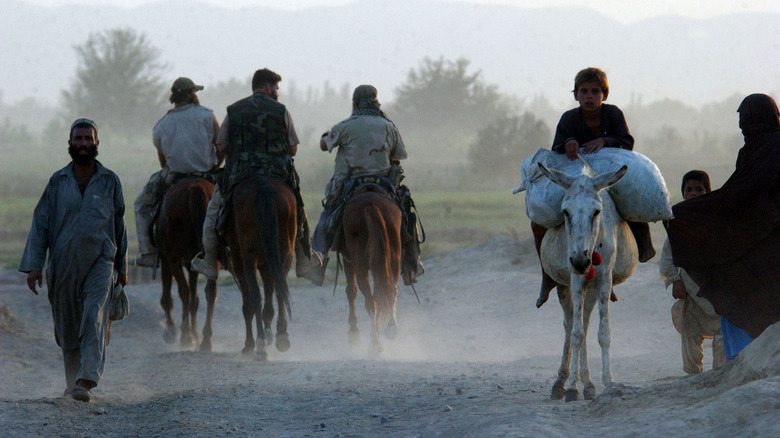 Green Berets riding horses past locals in Afghanistan