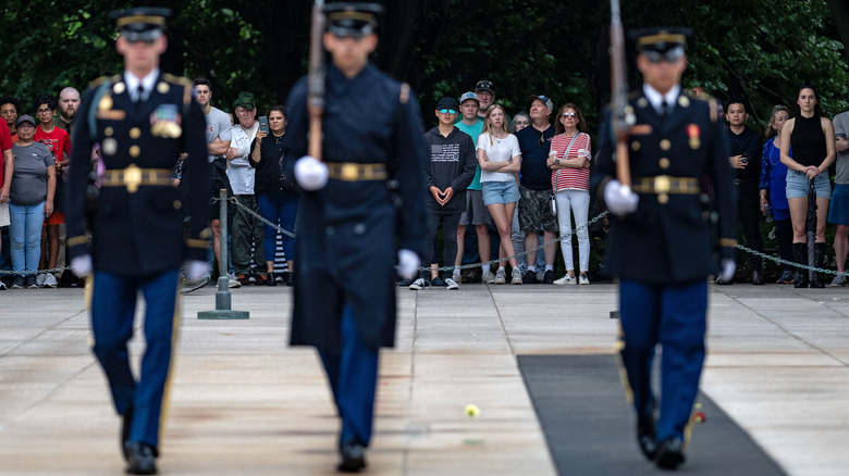 Three Guards march in front of a crowd