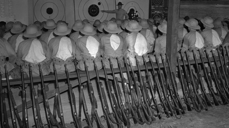 Rifles are stacked behind Marines during training