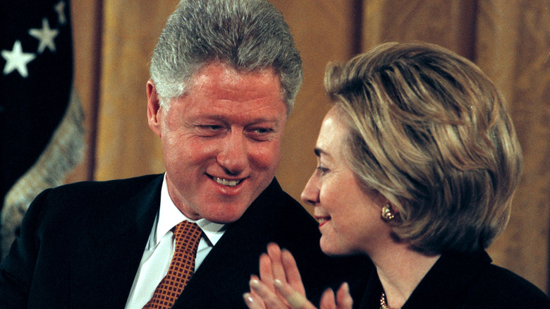 Bill Clinton smiling and Hillary Clinton applauding