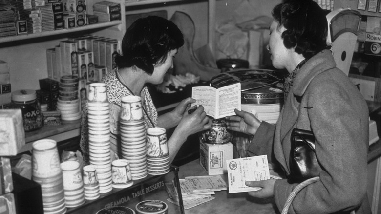 Women inspect ration books in a store.