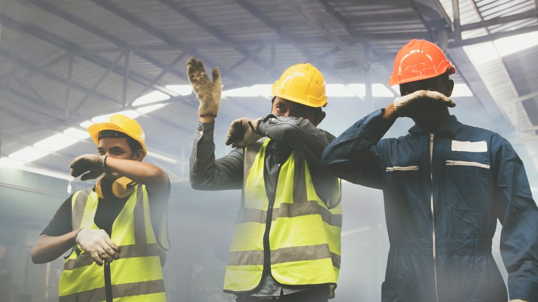 Workers with hands over noses