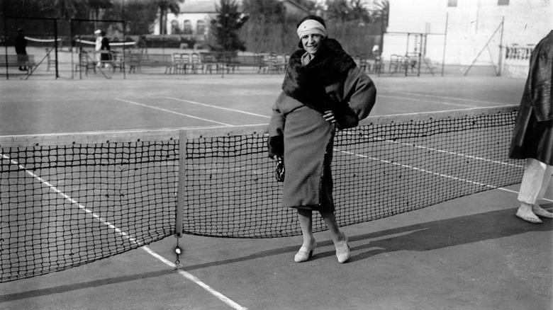 Suzanne Lenglen in a fashionable coat on a tennis court