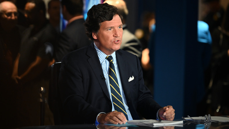 Tucker Carlson seated behind desk