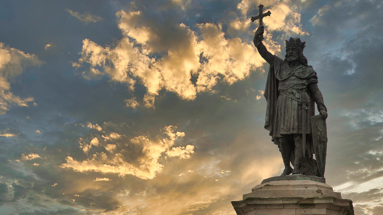 Statue of Don Pelayo Gijon holding up cross clouds