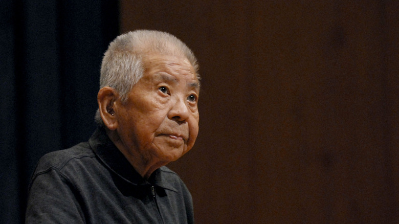 Elderly Tsutomo Yamaguchi looks into distance with neutral expression.