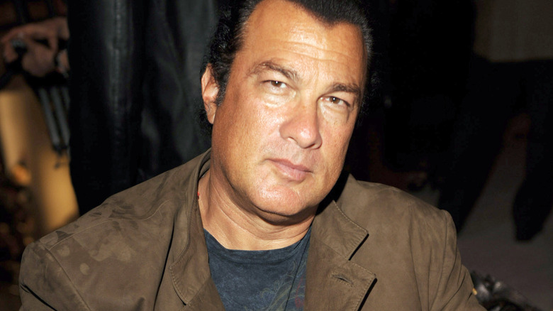 Steven Seagal in a black shirt and tan jacket