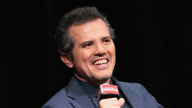 John Leguizamo smiling speaking into a microphone