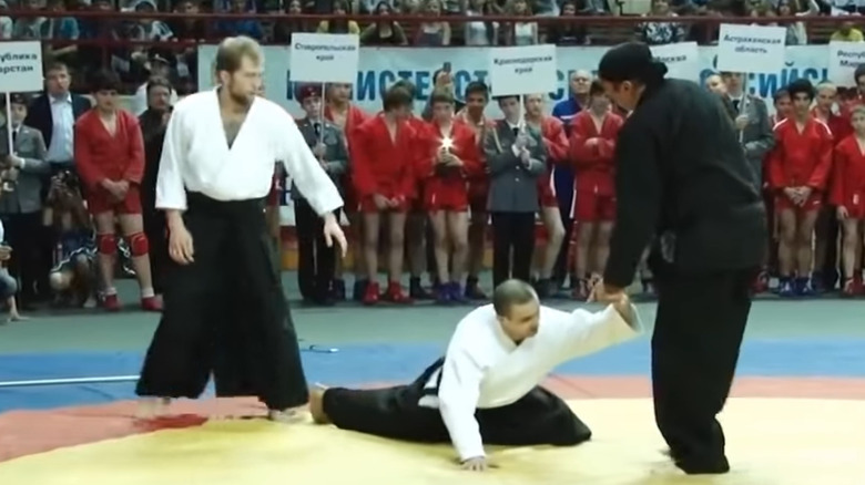 Steven Seagal grappling with one opponent while another looks on