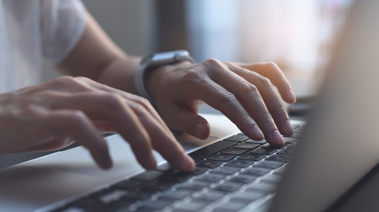 Person's hands typing on a laptop