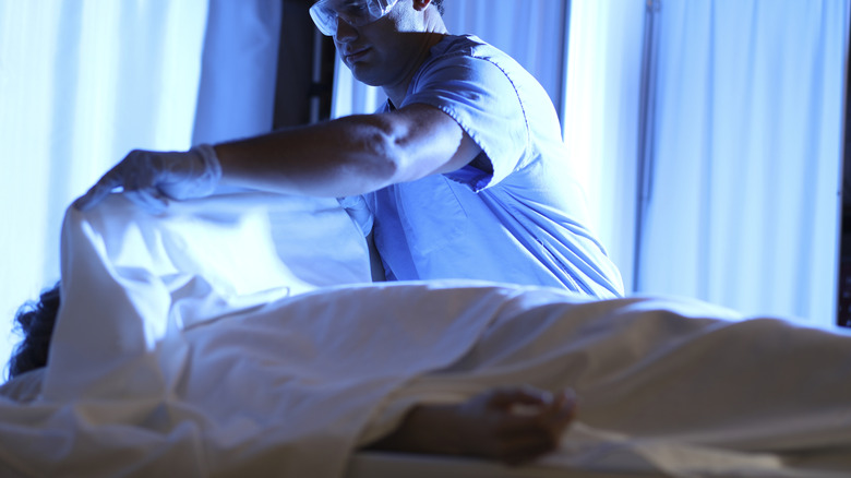 Medical worker covering body with sheet