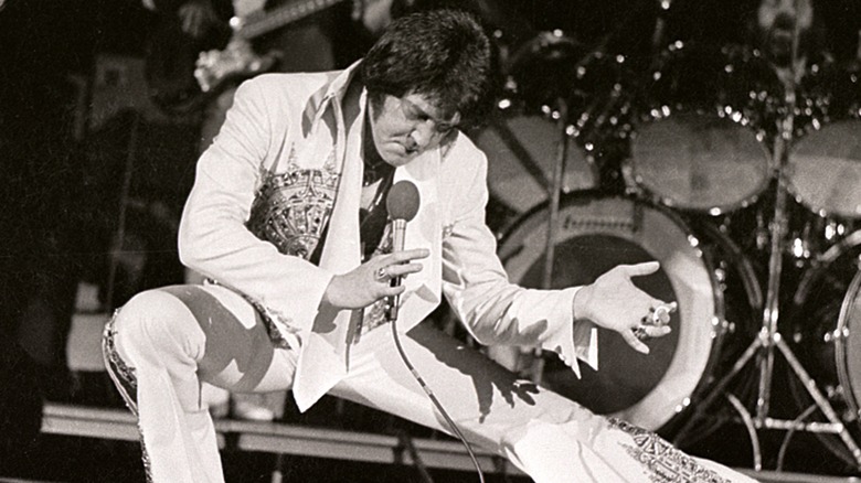 Elvis Presley crouching on stage performing
