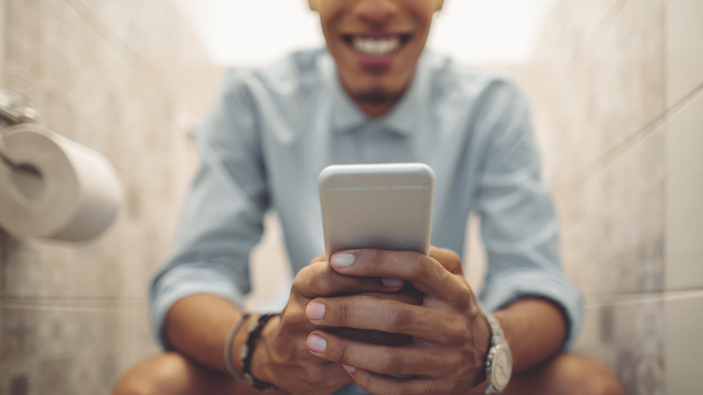 guy checking phone on toilet