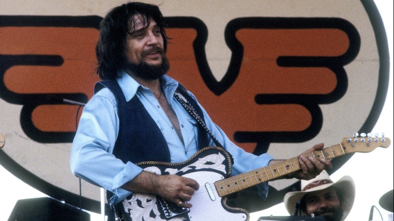 Waylon Jennings playing guitar onstage