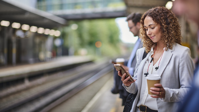 woman with cell phone waiting for a train