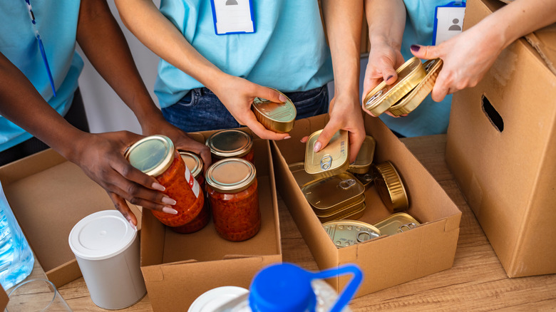 People putting canned food in boxes